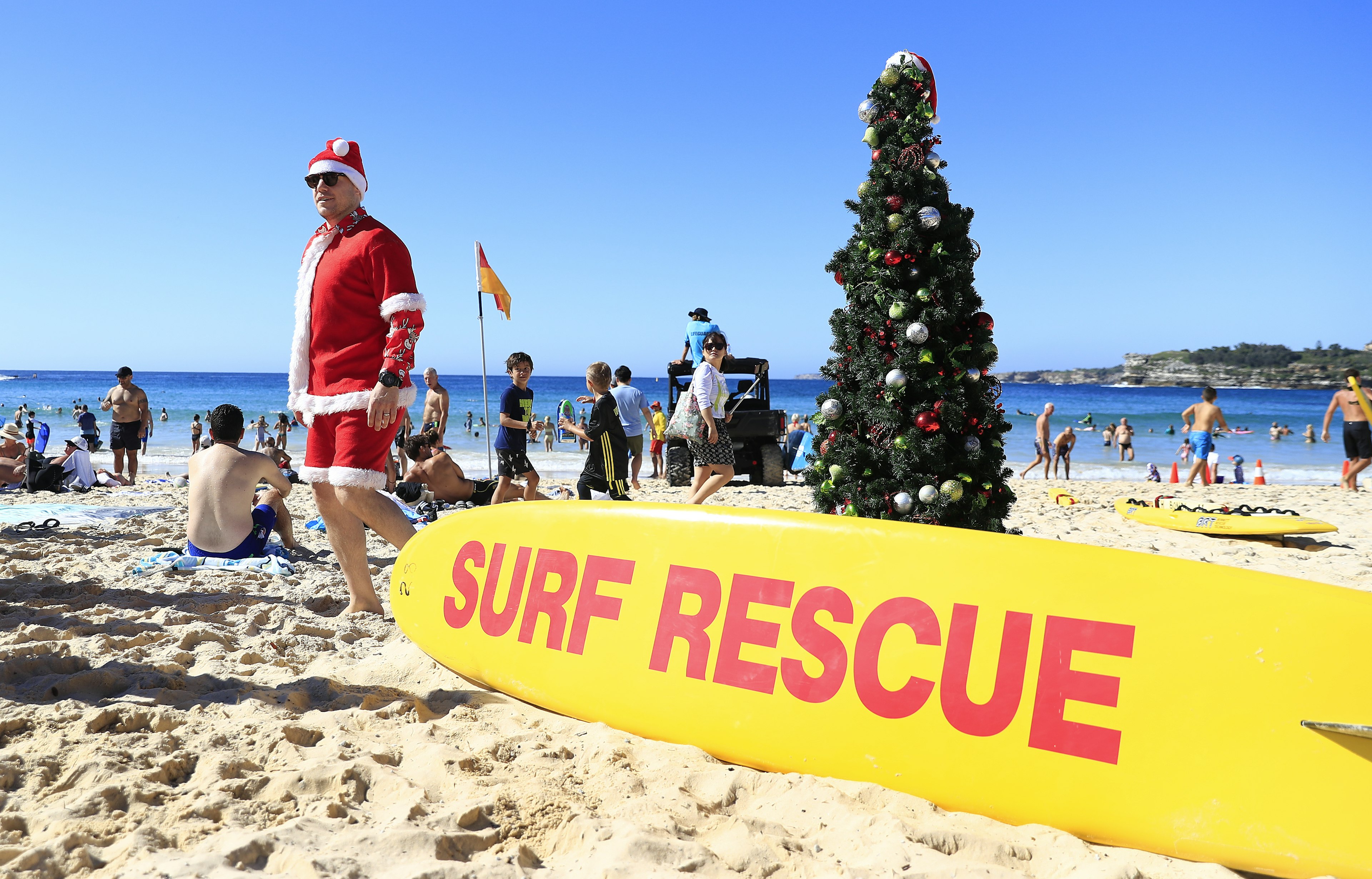 SYDNEY, AUSTRALIA - DECEMBER 25: A man dressed  as Santa poses next to a Christmas tree on Bondi Beach on December 25, 2018 in Sydney, Australia. December is one of the hottest months of the year across Australia, with Christmas Day traditionally involving a trip to the beach and celebrations outdoors. (Photo by Mark Evans/Getty Images)