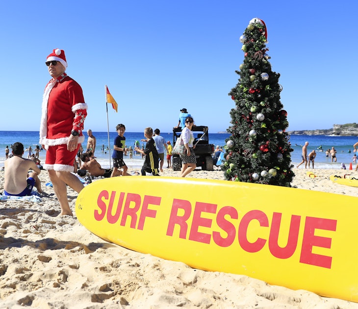 SYDNEY, AUSTRALIA - DECEMBER 25: A man dressed  as Santa poses next to a Christmas tree on Bondi Beach on December 25, 2018 in Sydney, Australia. December is one of the hottest months of the year across Australia, with Christmas Day traditionally involving a trip to the beach and celebrations outdoors. (Photo by Mark Evans/Getty Images)