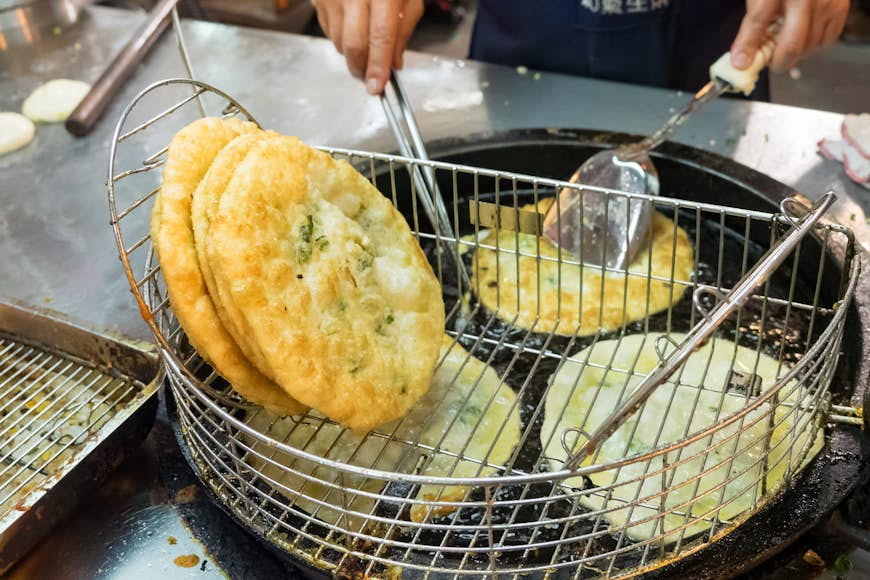 A green onion pancake in a metal bowl having just been cooked in Taiwan as street food