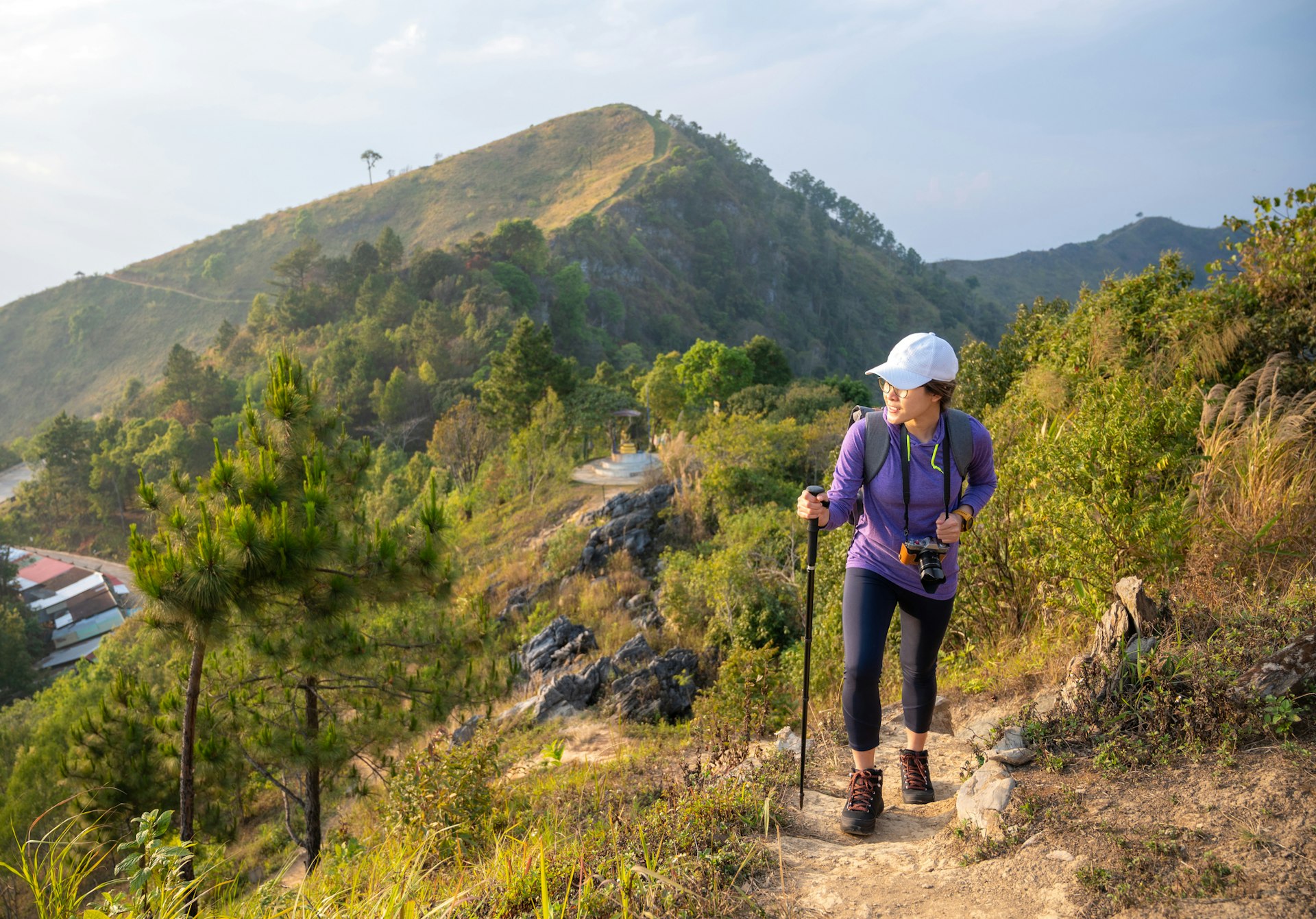 Young Asian woman while hiking on a mountain with a high cliff in Thailand