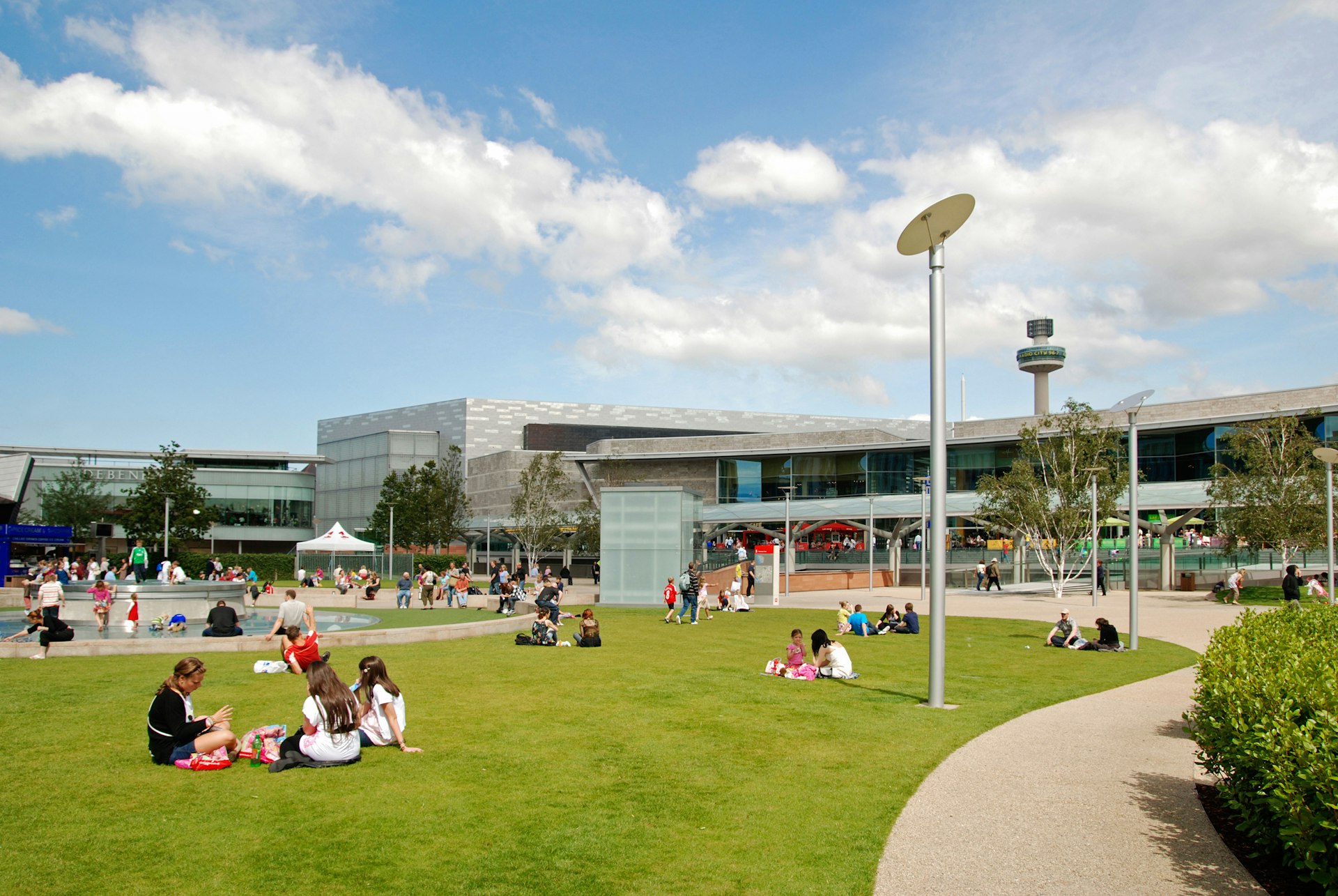 People sitting in the grass in Chavasse Park in Liverpool, England, on a sunny day