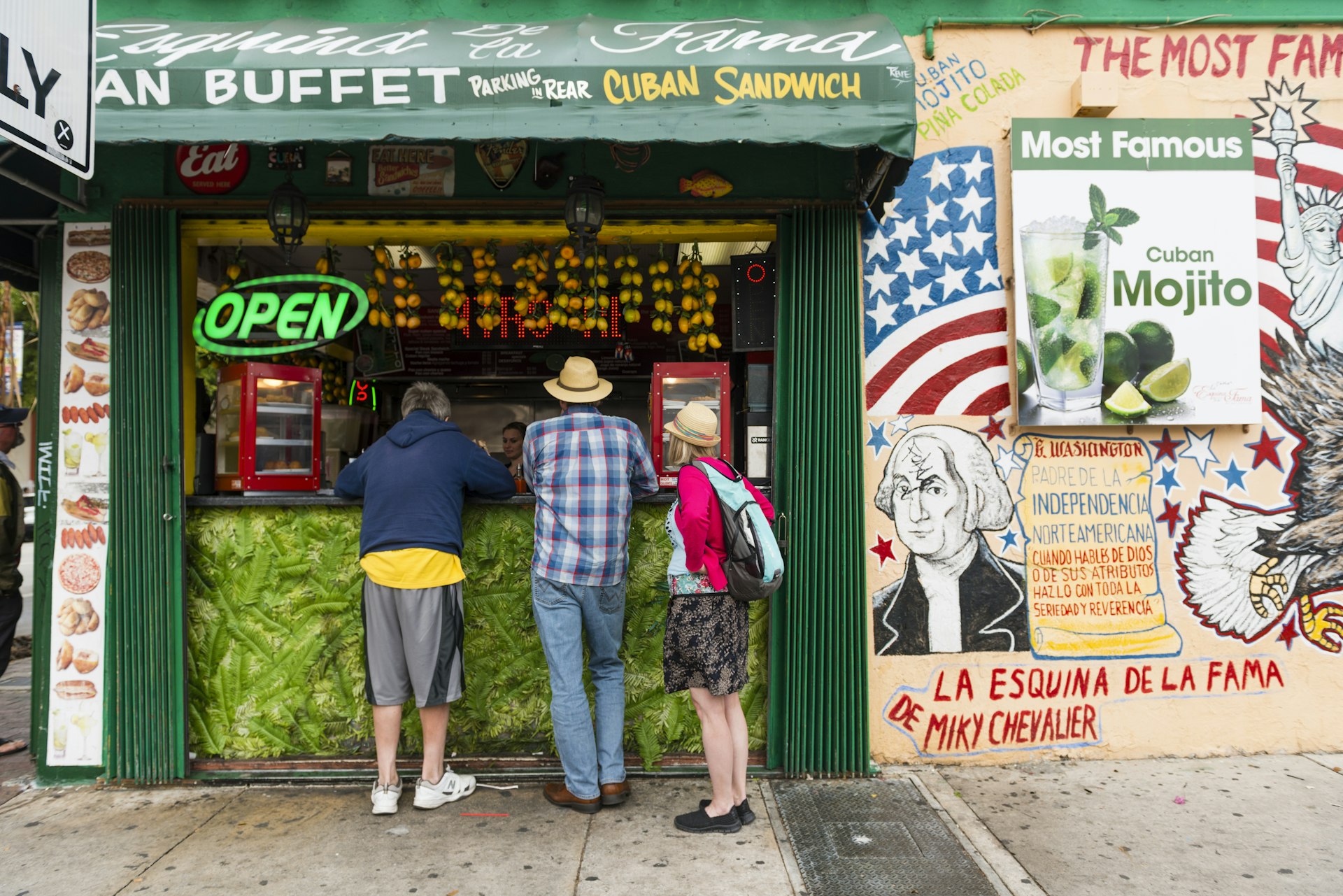 Tourists stand to order from the open air countertop of a restaurant advertising Cuban food and drinks on historic Calle Ocho in Little Havana.
