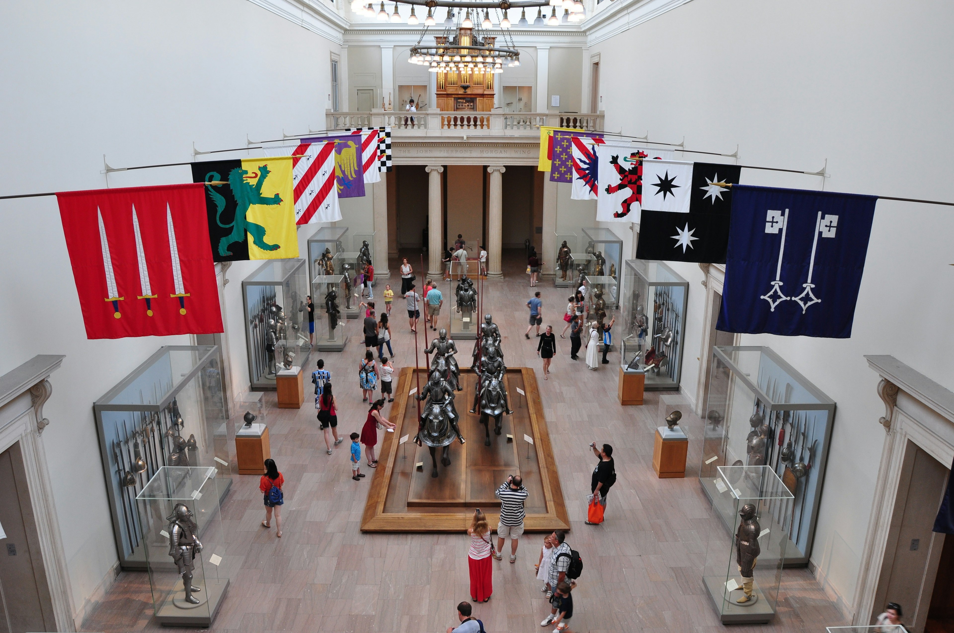 A gallery lined with cases full of armor, helmets and spears. The centerpiece is soldiers on armored horses