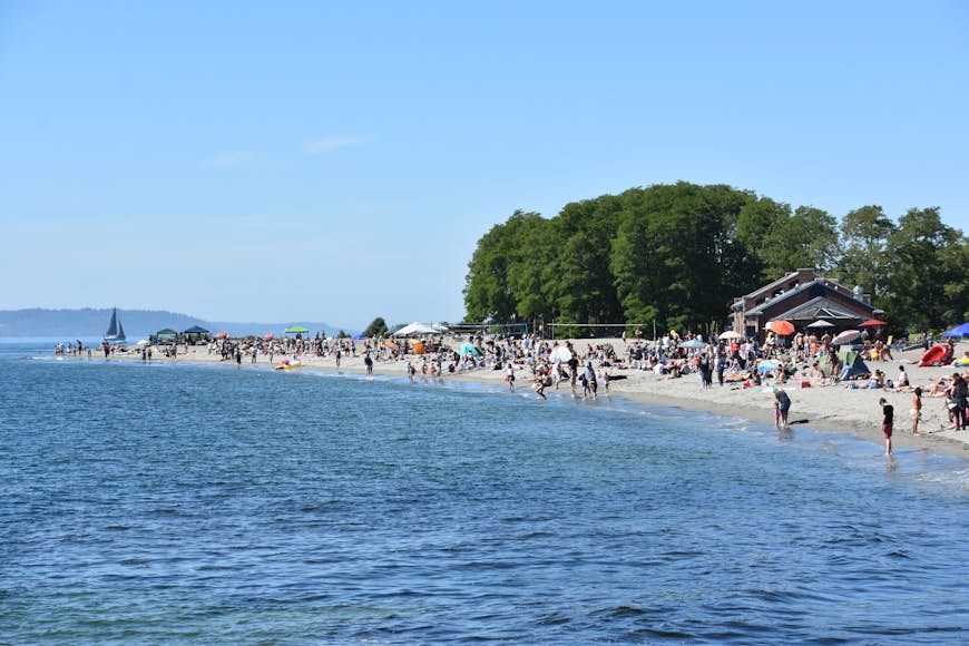 Groups of people line the waterside at Golden Gardens beach