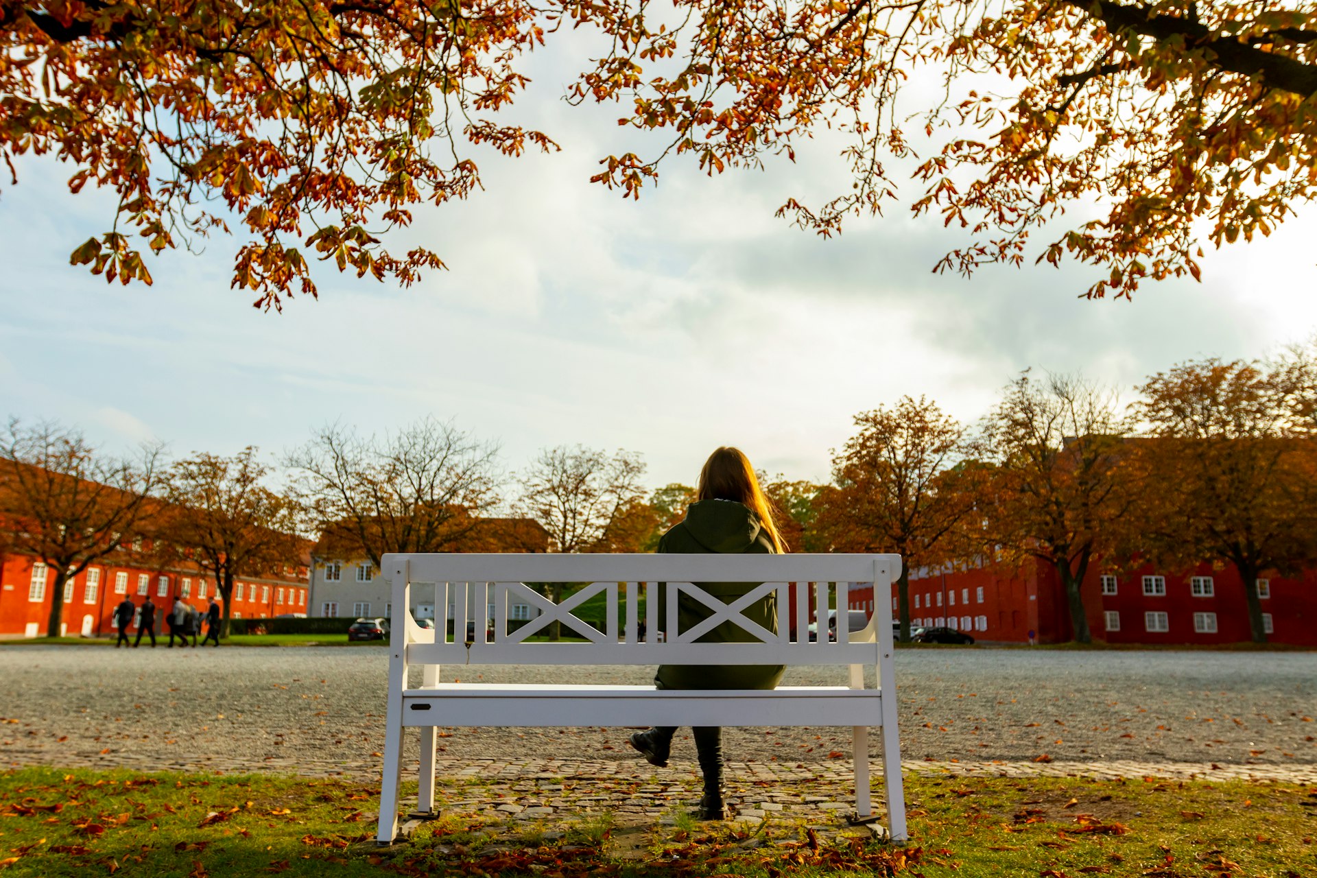 A woman sitting on a bench under a tree at Kastellet fortress in Copenhagen, Denmark
