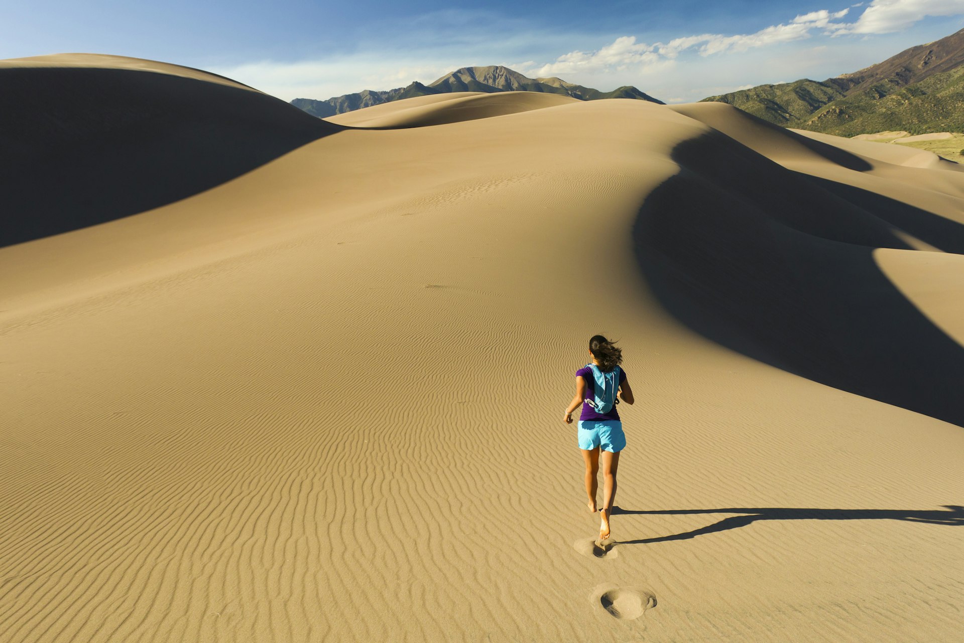 Woman running on sand dune in Great Sand Dunes National Park, Colorado
