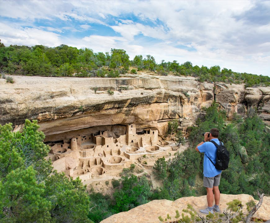 Man on vacation taking photos of the Ancestral Puebloan cliff dwellings at Mesa Verde National Park in Colorado