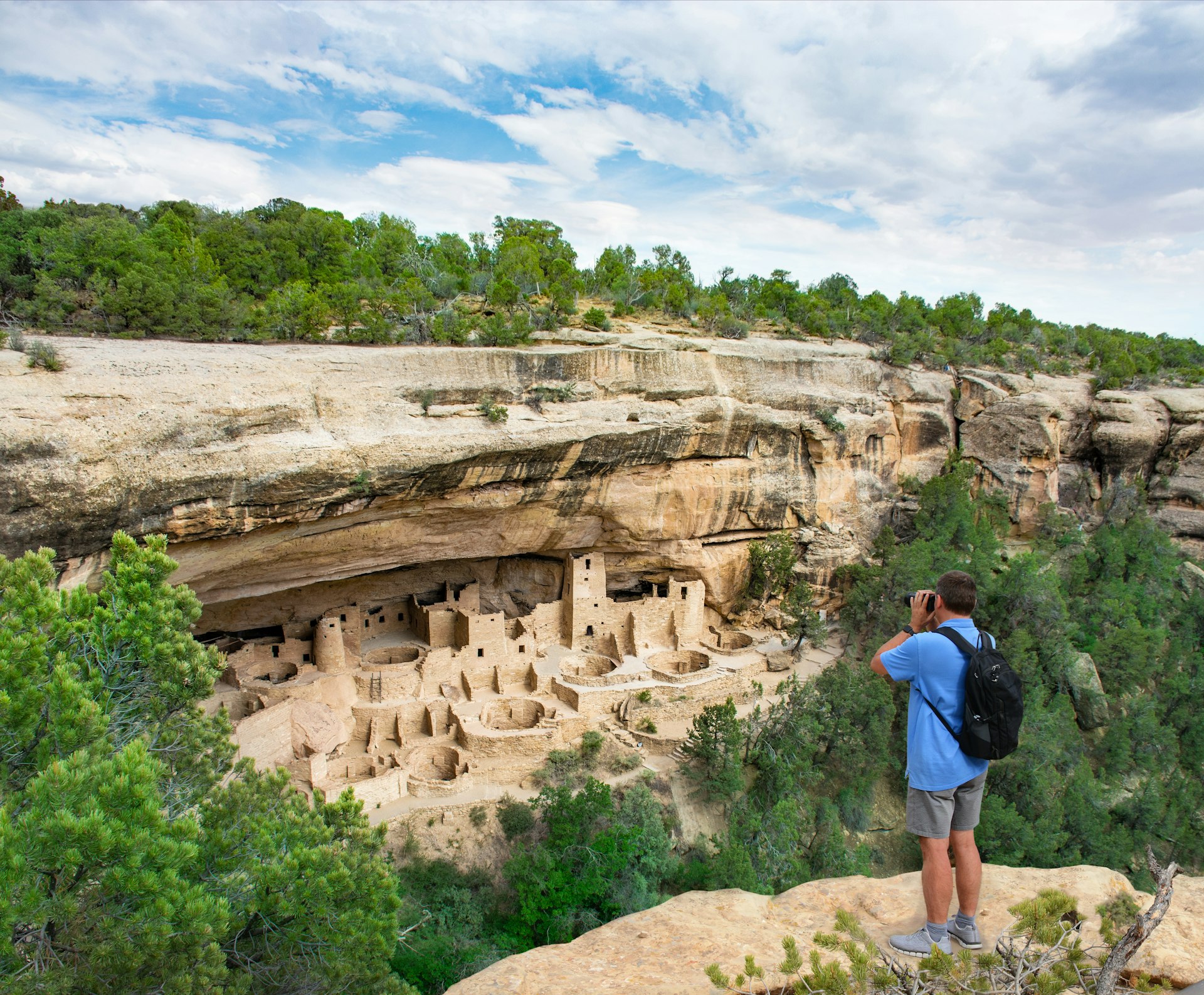 Man on vacation taking photos of the Ancestral Puebloan cliff dwellings at Mesa Verde National Park in Colorado
