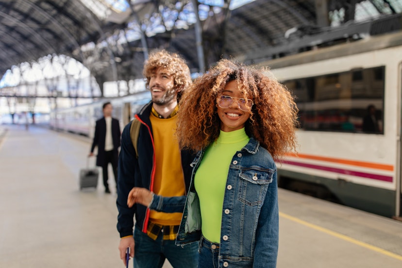 Young multi-ethnic couple waiting for train on platform at train station in Spain