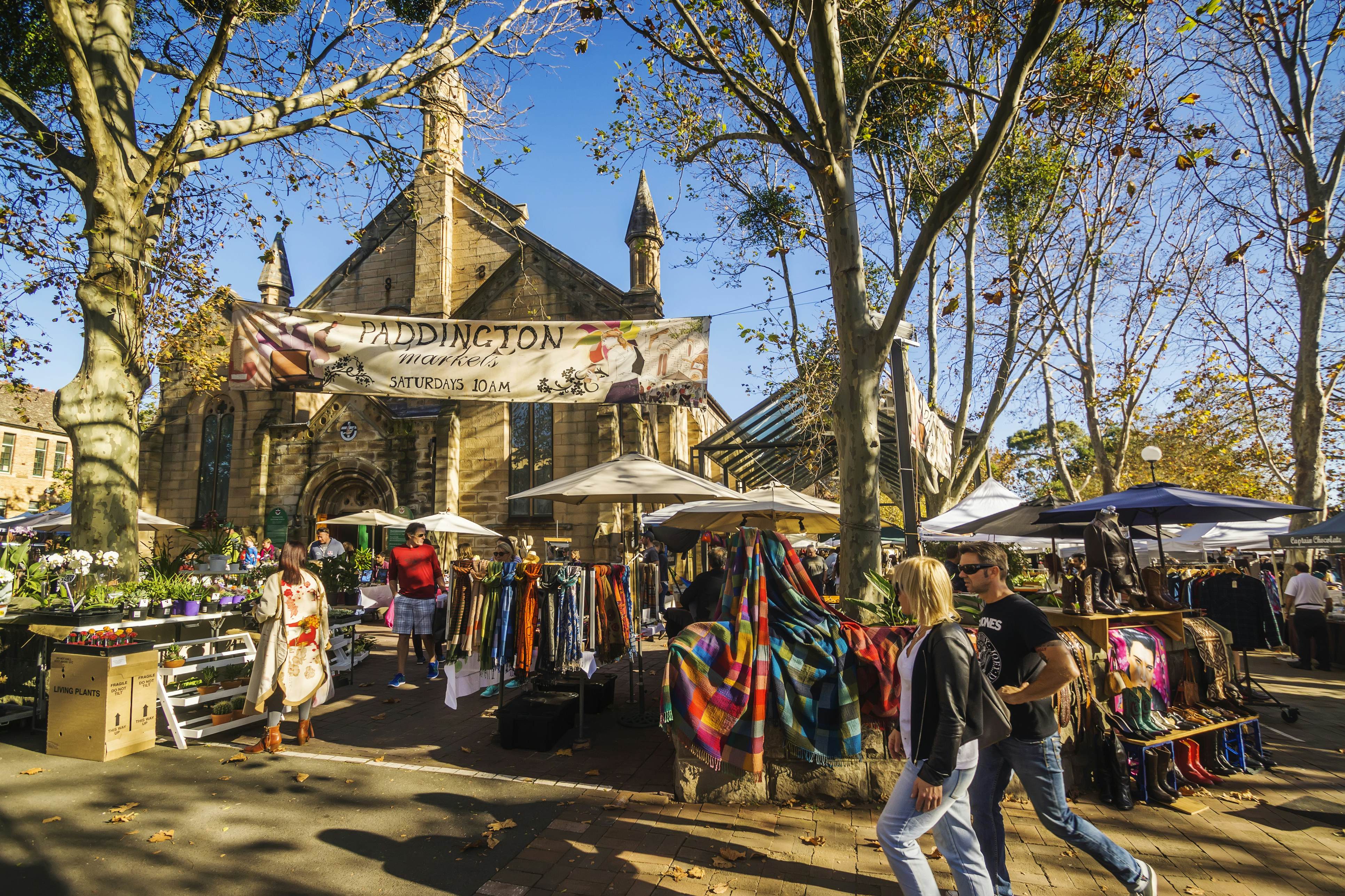 A man and woman walk past stalls at the Paddington Markets, a long-running weekend market held at the Paddington Public School.