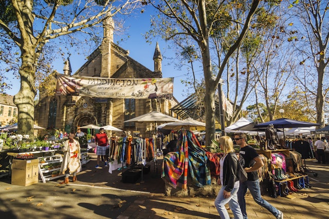 A man and woman walk past stalls at the Paddington Markets, a long-running weekend market held at the Paddington Public School.