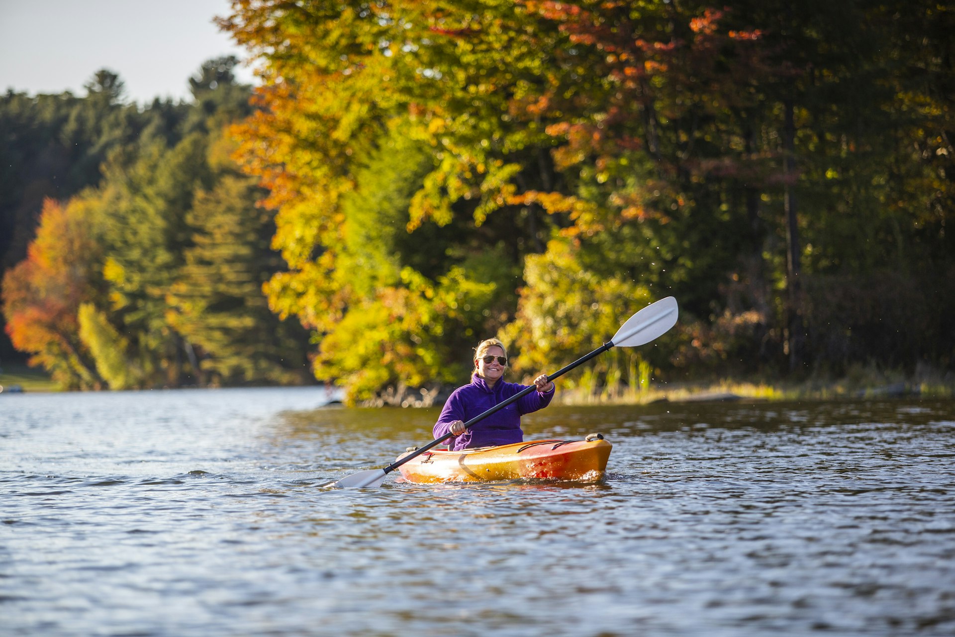 Woman kayaking on a lake during peak foliage, Silver Lake, Vermont, USA