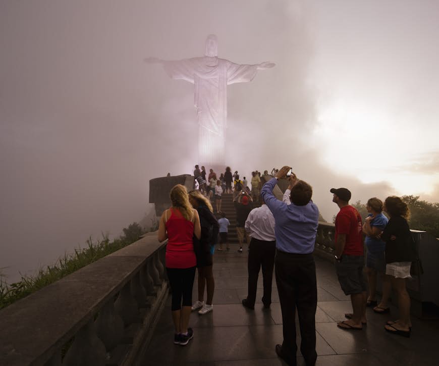 People looking at the Cristo Redentor statue on a foggy night