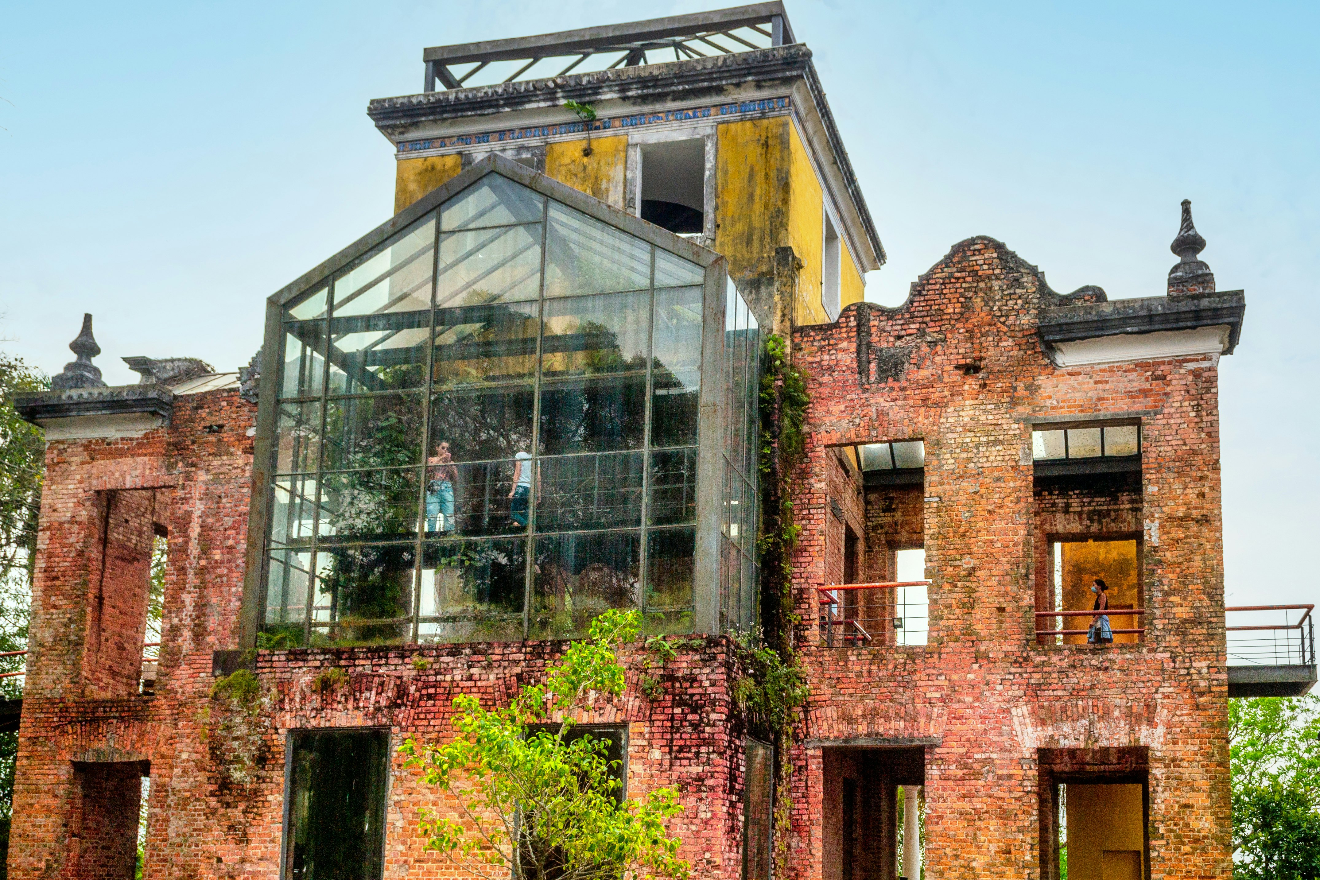 Low-angle view of people visiting a building that appears to be ruined but has modern glass section