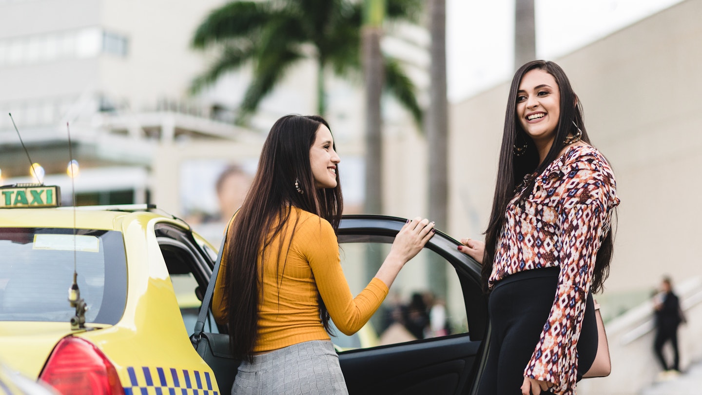 Pretty women talking at the door of a taxi
