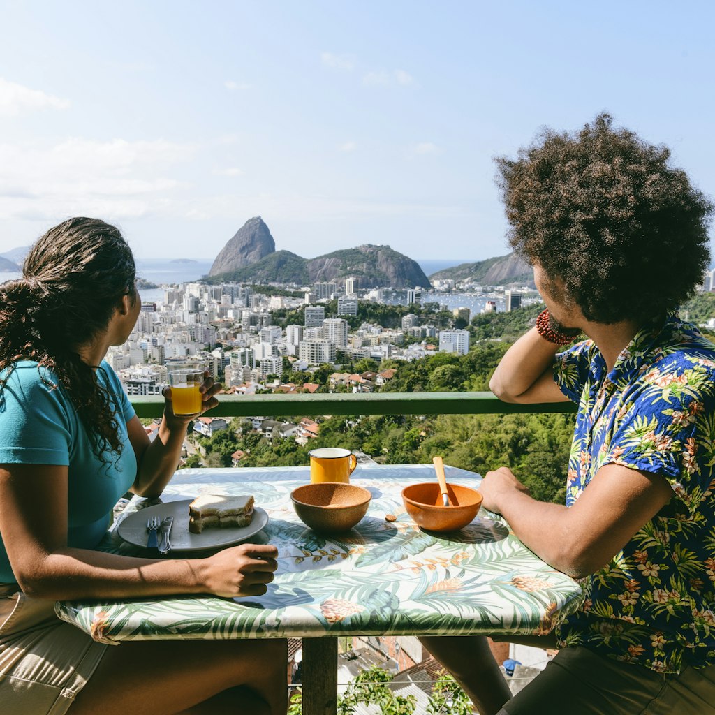 Couple on holiday in Rio de Janeiro, sitting at table, enjoying breakfast al fresco