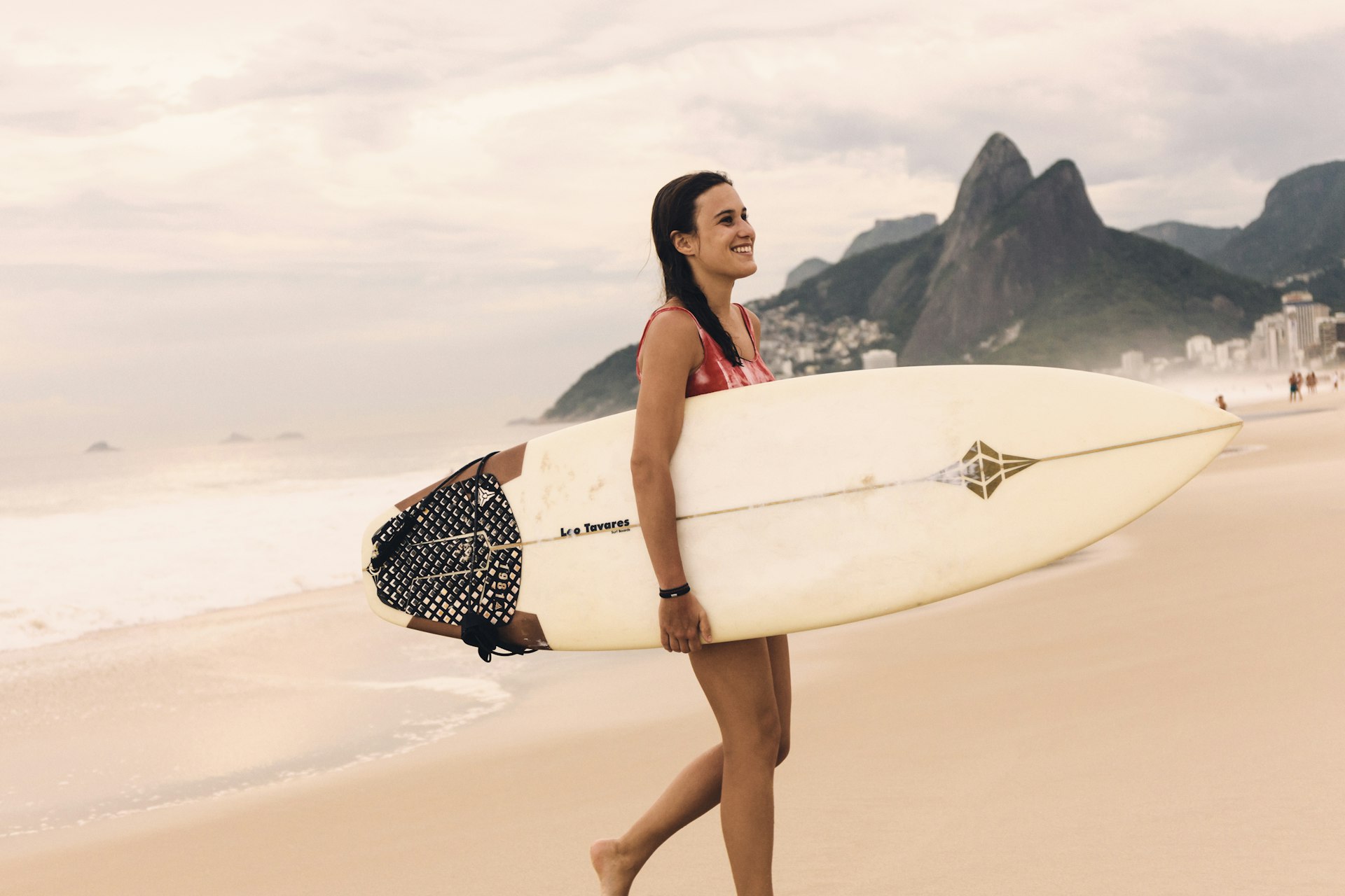 Young woman carrying surfboard at Ipanema Beach, Rio de Janeiro