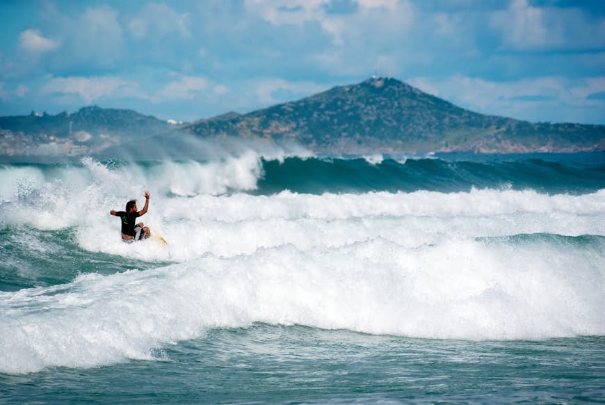 A surfer rides through the foamy waves of the Atlantic Ocean in Cabo Frio, Rio de Janeiro, Brazi