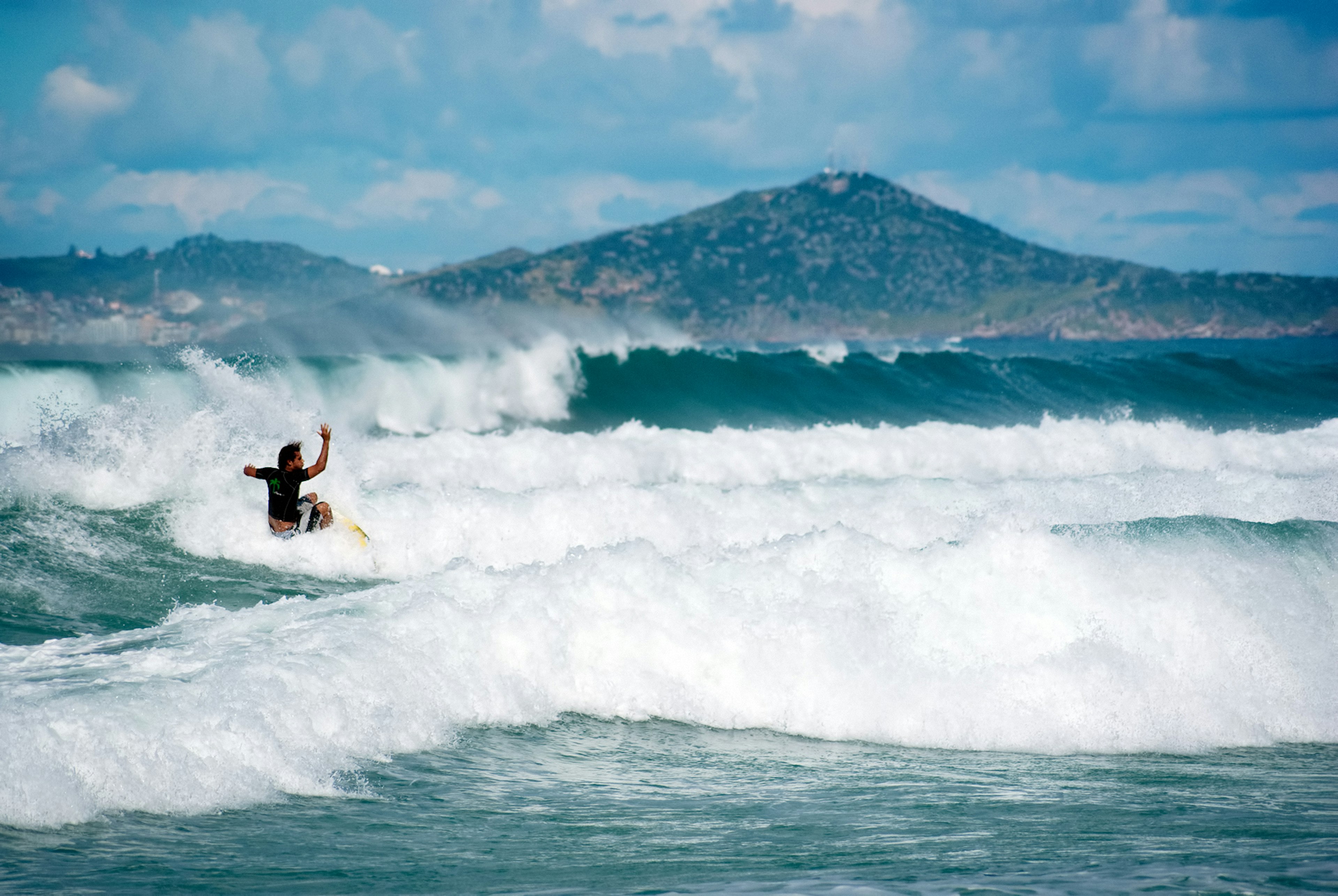 A surfer cuts through a frothy wave in Cabo Frio, Rio De Janeiro, Brazi