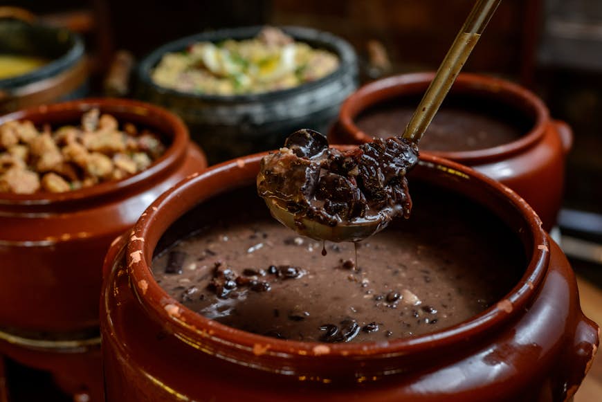 Bowl of feijoada on a table with other dishes in Brazil