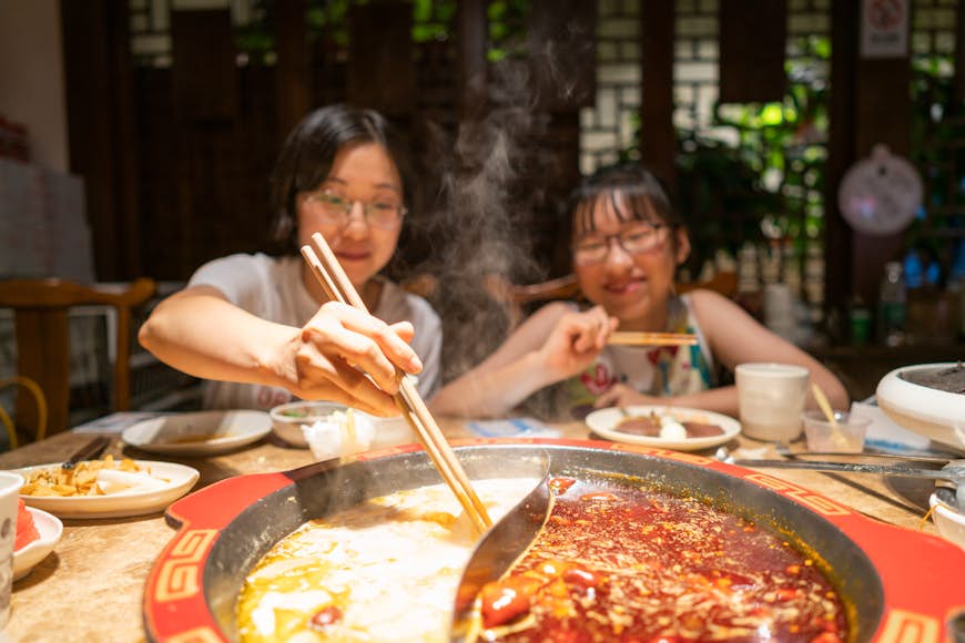 Мать и дочь едят жаркое в кастрюле в Нанкине, Китай.
