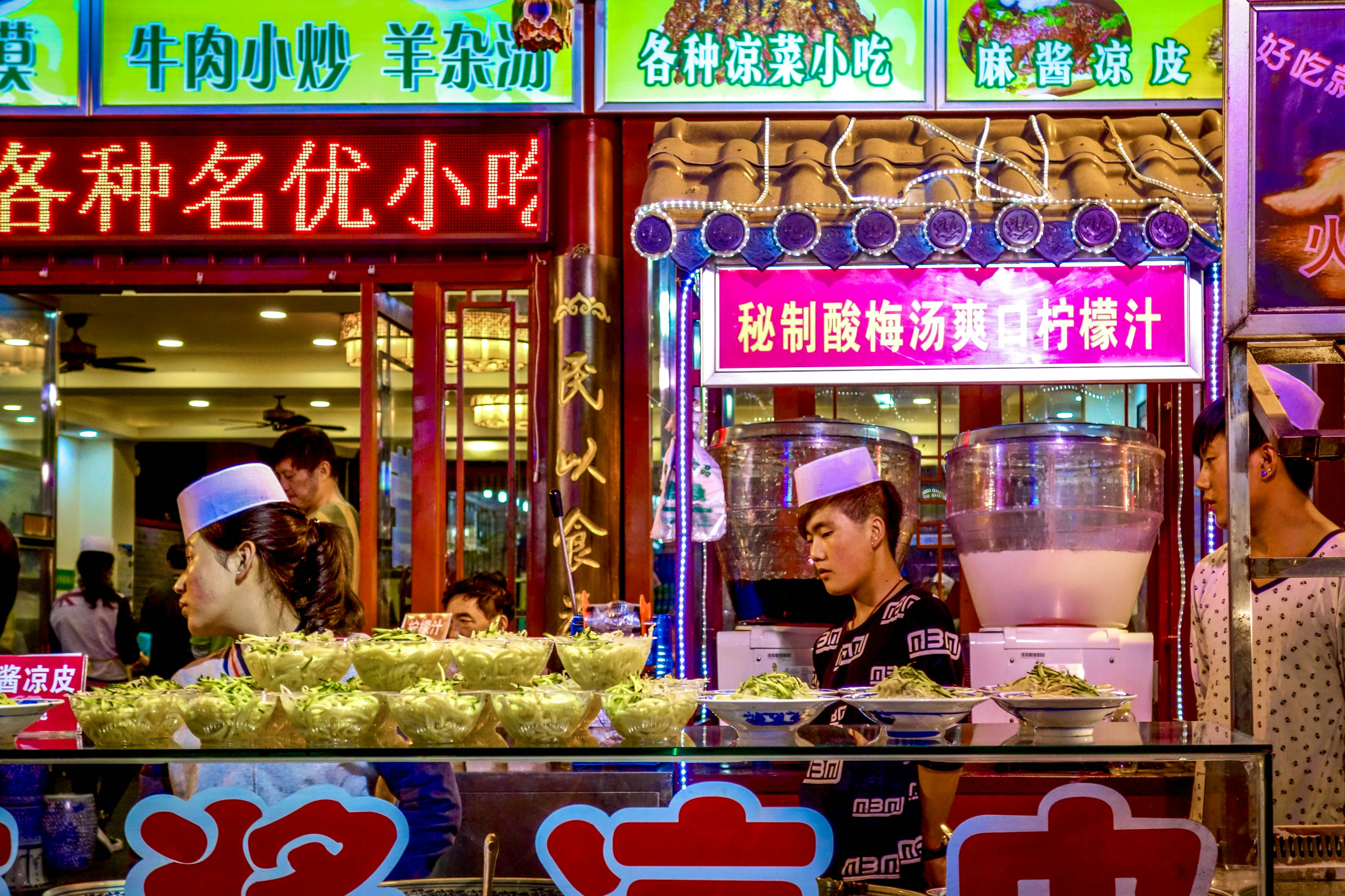 Xi'an, China - April 2015: Bowls of noodles for sale among bright neon signs at the Xian Muslim Street Market in Shaanxi province, China