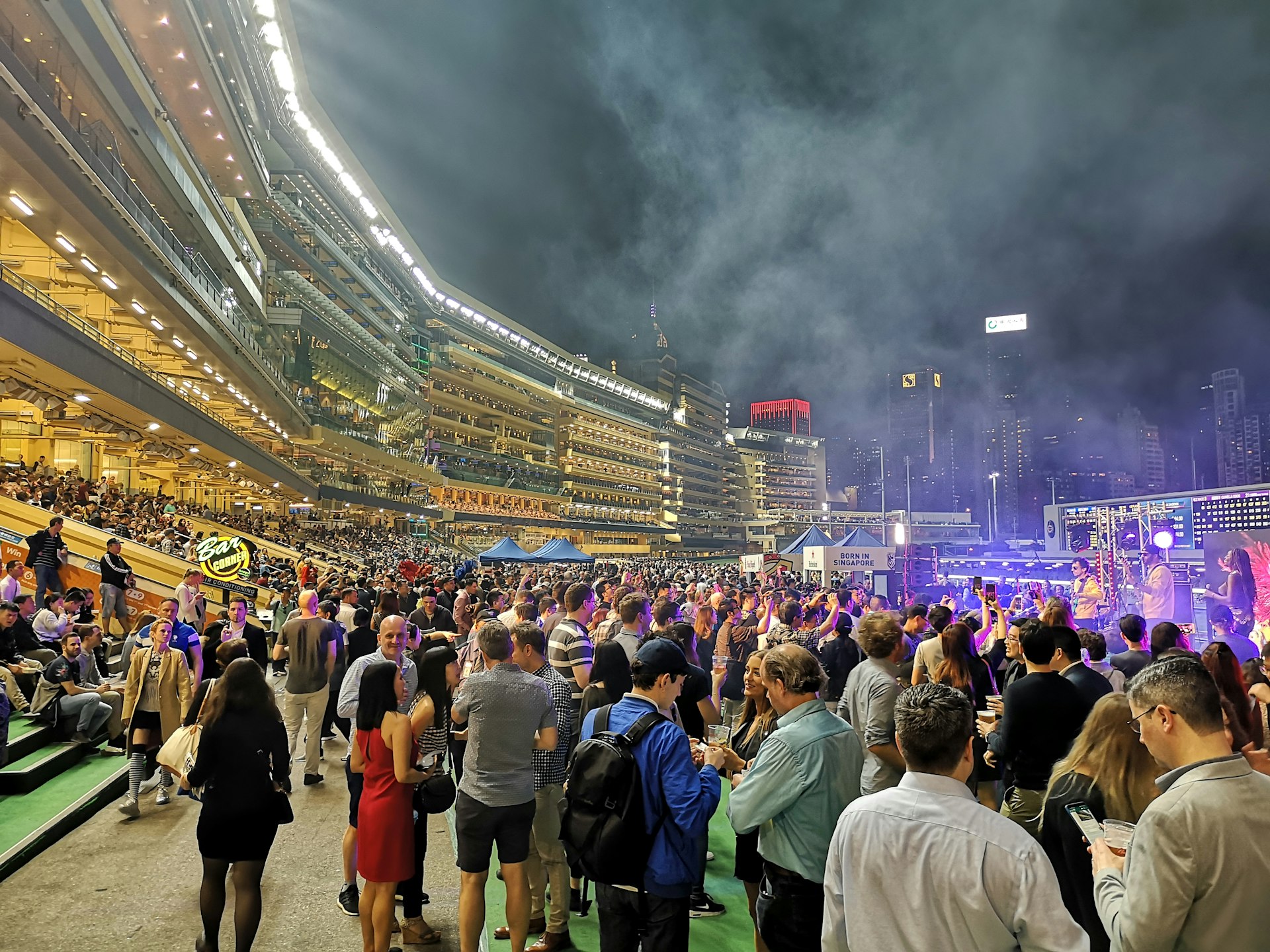 Fans stand in a crowd at the famous Happy Valley racecourse, used by the Hong Kong Jockey Club for horse racing meets, at night