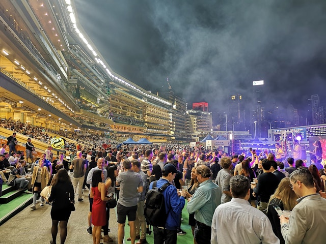 Fans stand in a crowd at the famous Happy Valley racecourse, used by the Hong Kong Jockey Club for horse racing meets, at night