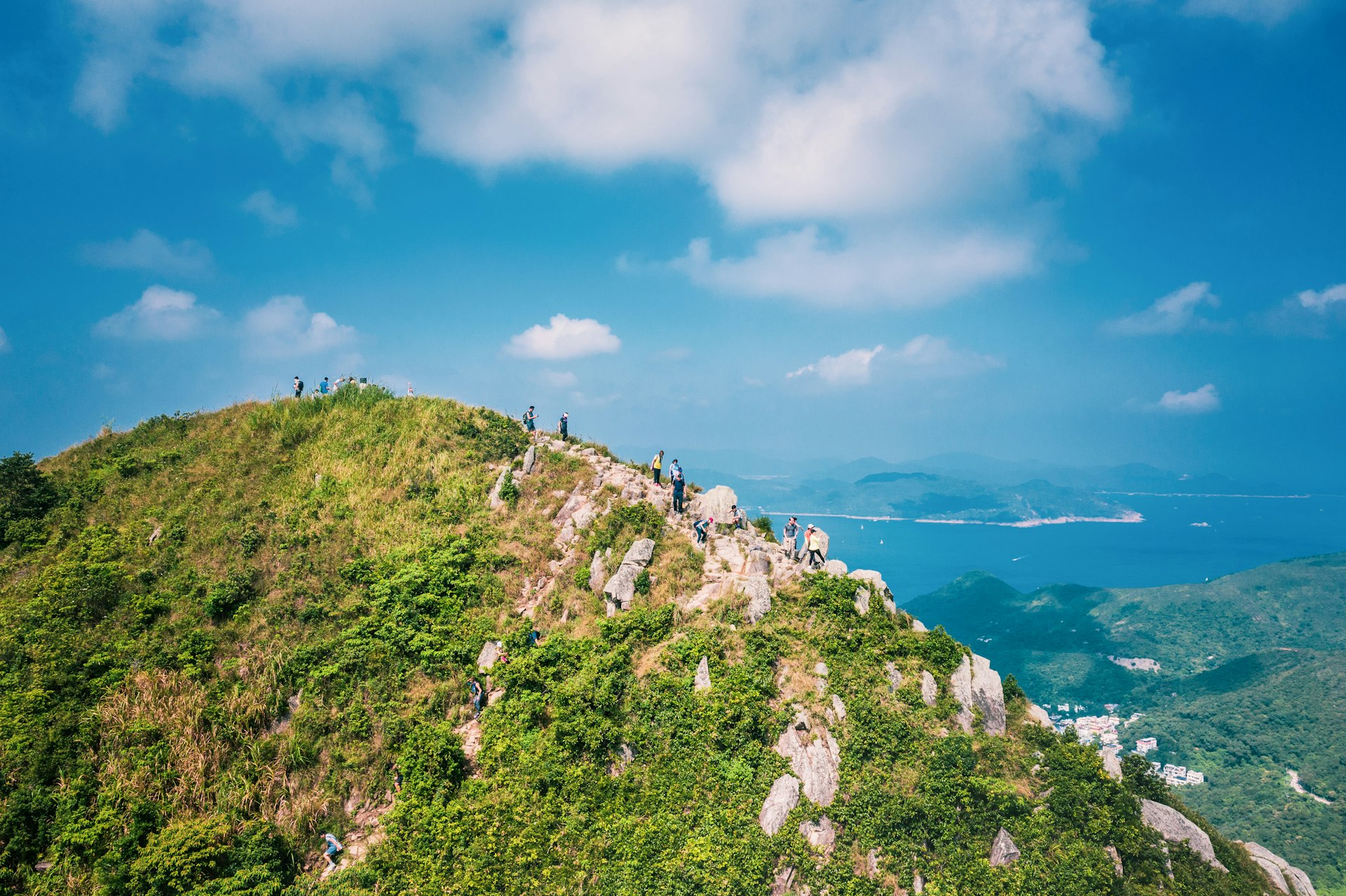 People walking on a path on a jagged mountain on a sunny day in Sai Kung, Hong Kong