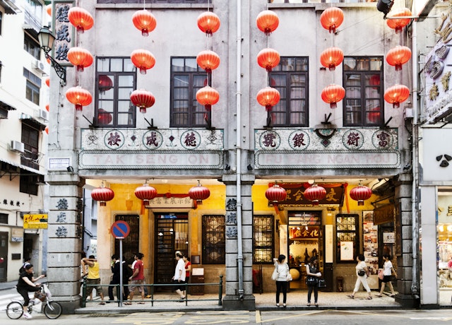 People walking in front of an old building with lanterns in the historic centre of Macau