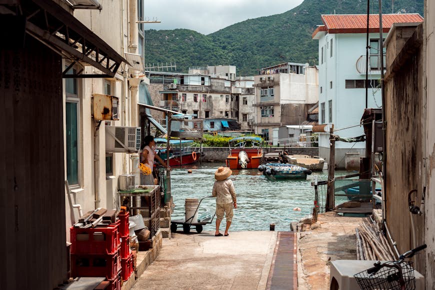 Person stands with a cart near the water at Tai O Fishing Village, Hong Kong