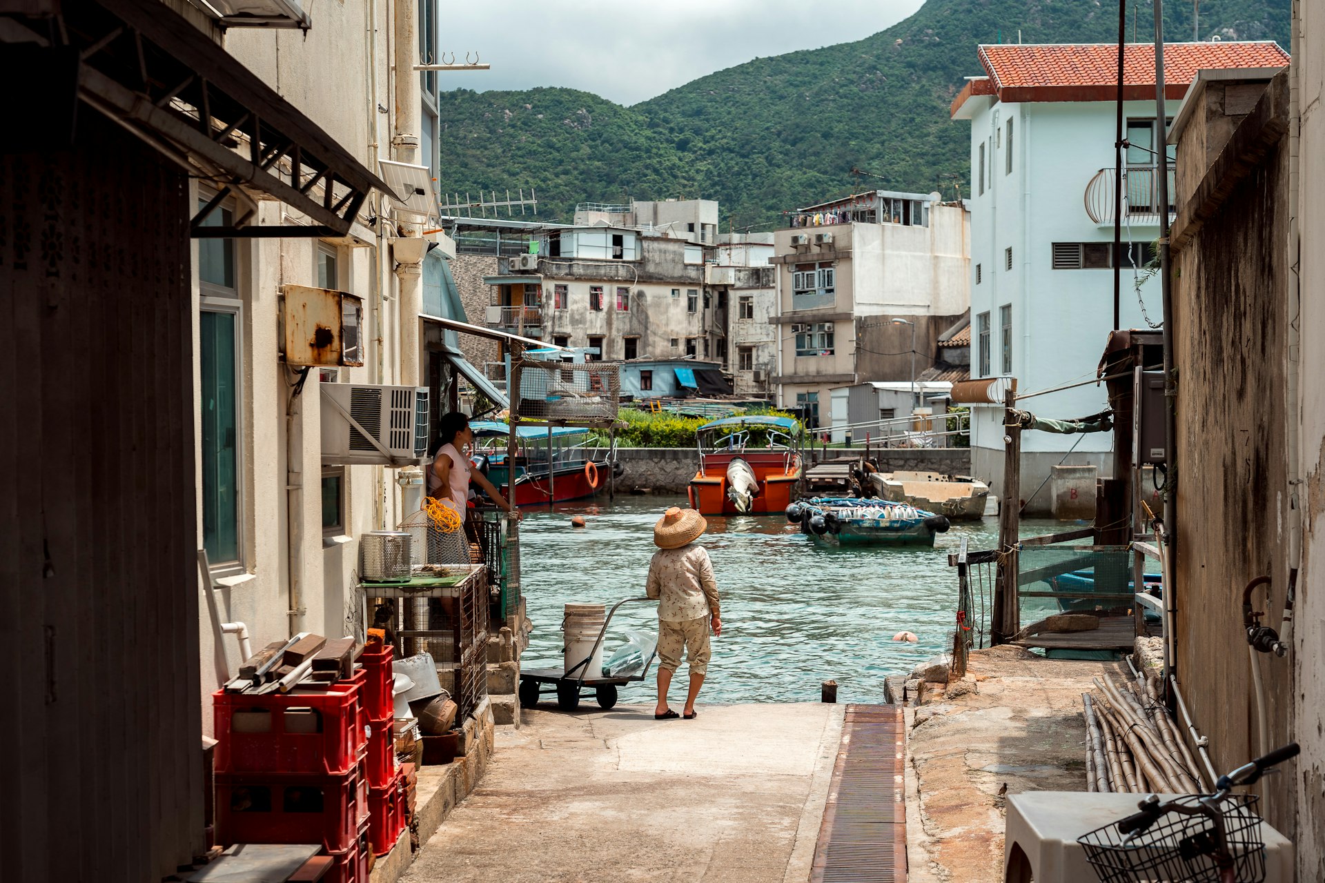Person stands with a cart near the water at Tai O Fishing Village, Hong Kong