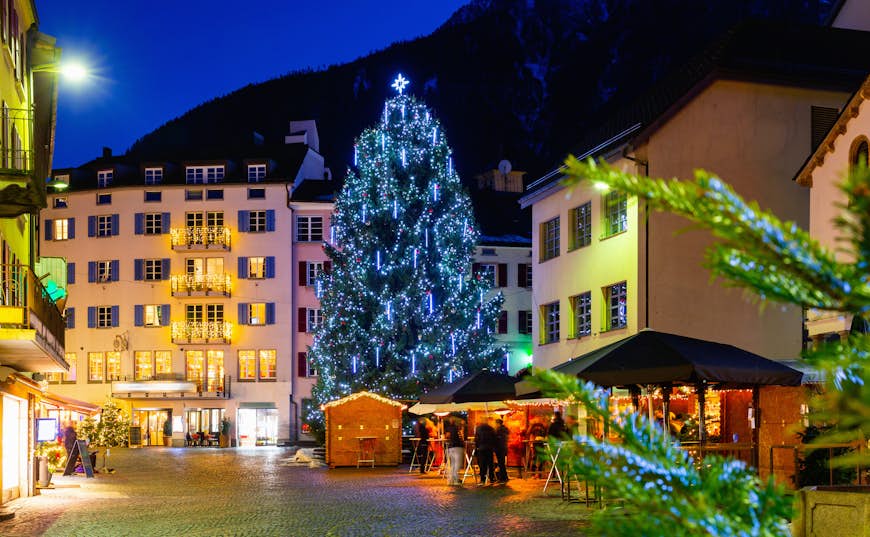Vista notturna di Brig Street con albero di Natale sullo sfondo delle Alpi, Svizzera