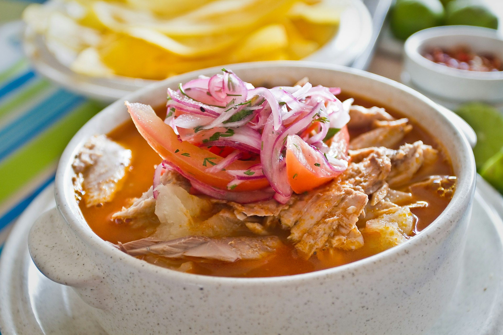 Encebollado: a fish stew in a bowl served with banana chips and lemon