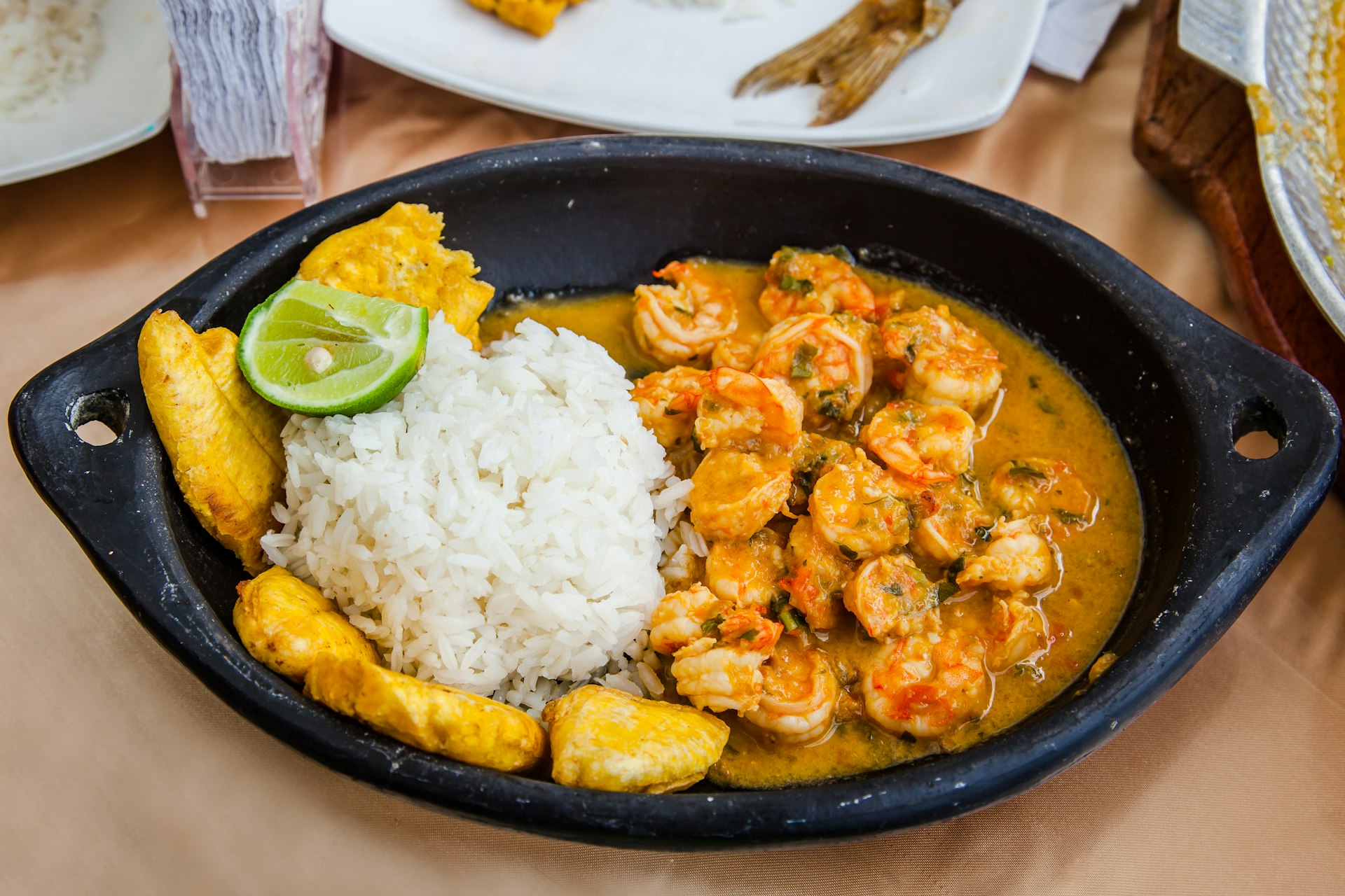 Coconut shrimp stew (encocado), served in earthenware dish, with rice and fried plantains