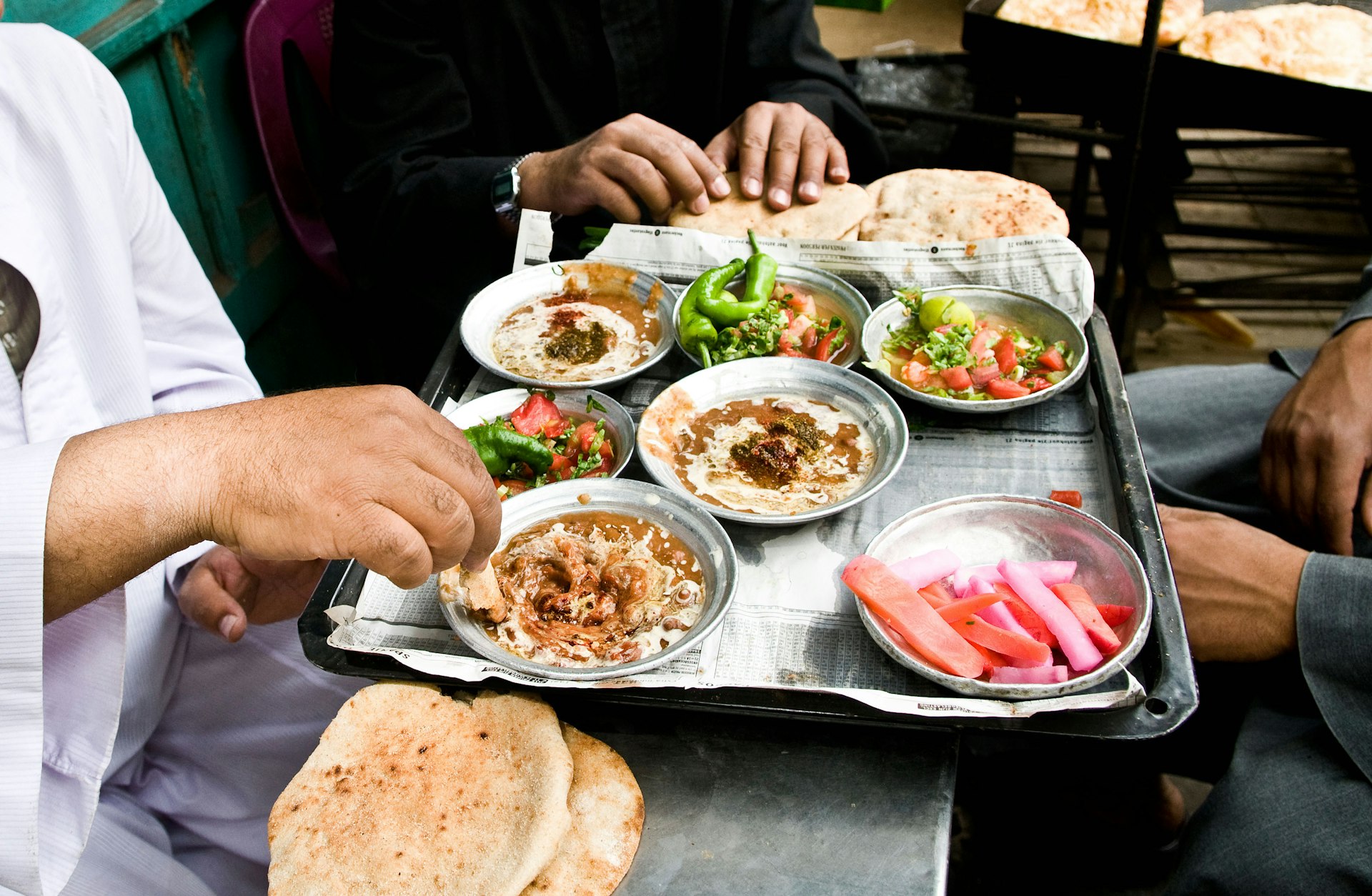People in Egypt passing a tray with several dishes, including fuul medames