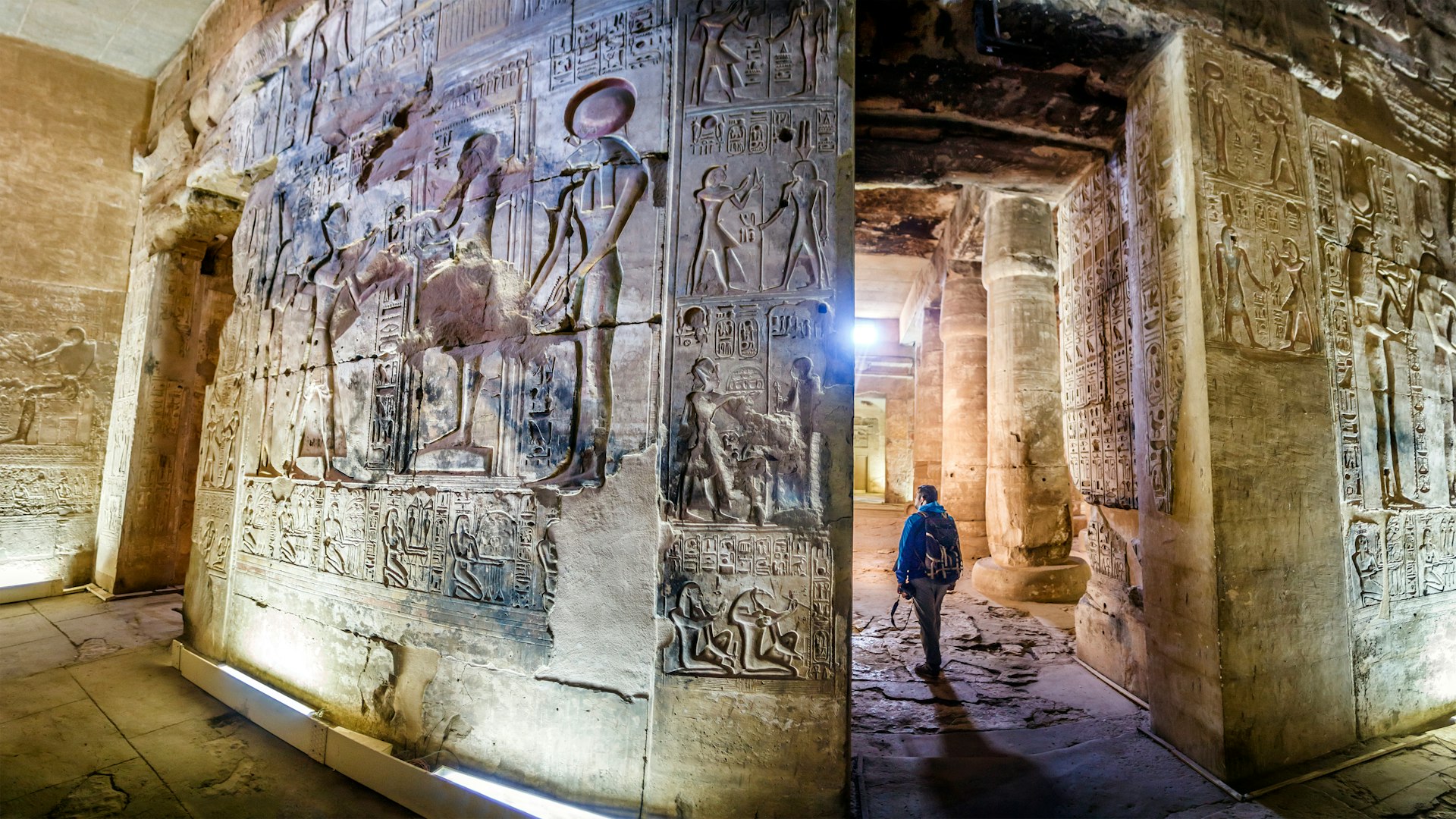 Detailed relief hieroglyps on a temple wall as a person walks by