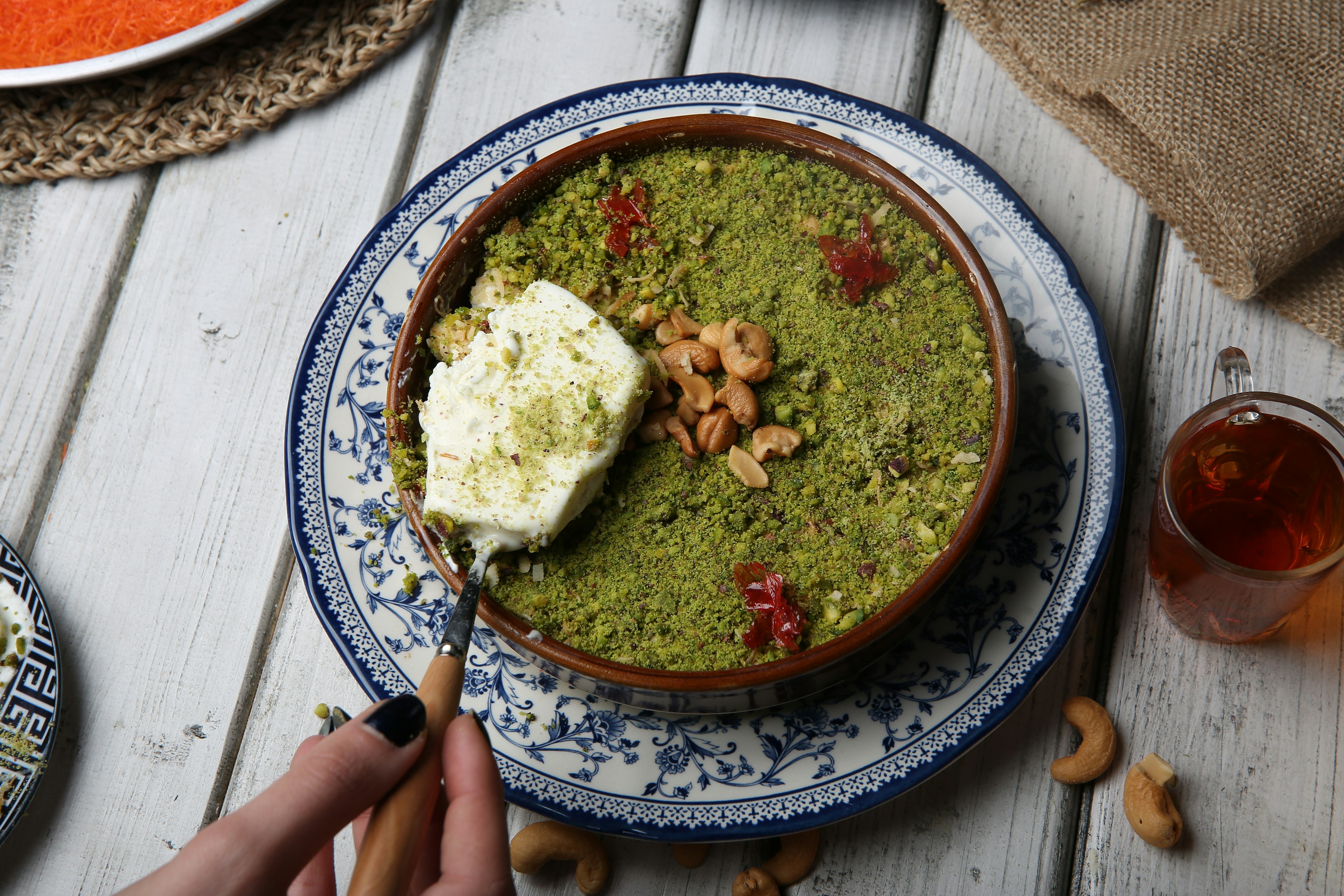 A hand holding a scoop of ice cream over a plate of oum ali, a popular dessert in Egypt