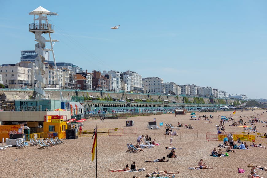Crowds playing, sunbathing, and swimming at Brighton Beach in the summertime