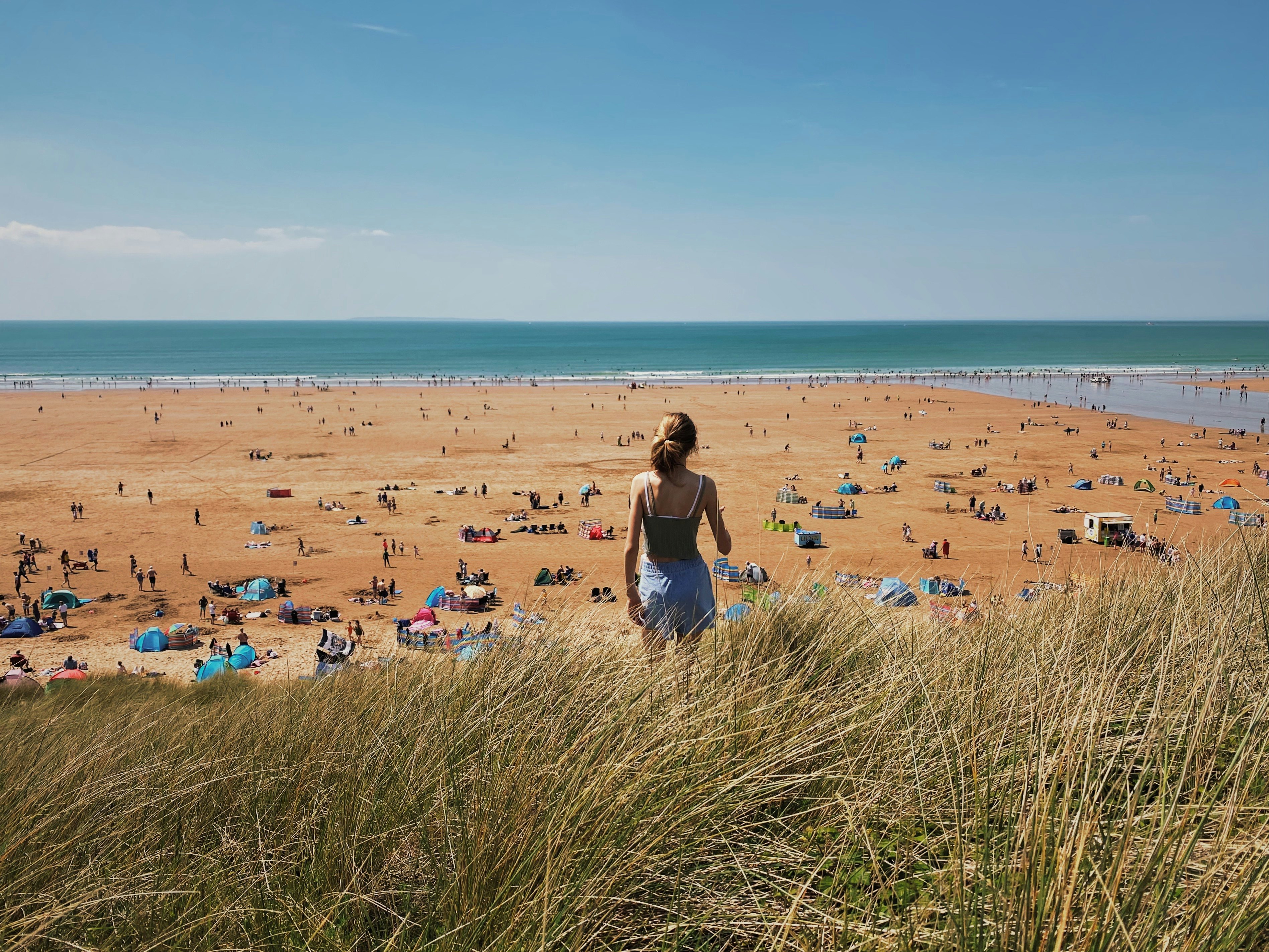 Rear view of a girl on vacation looking out onto a busy beach in Devon