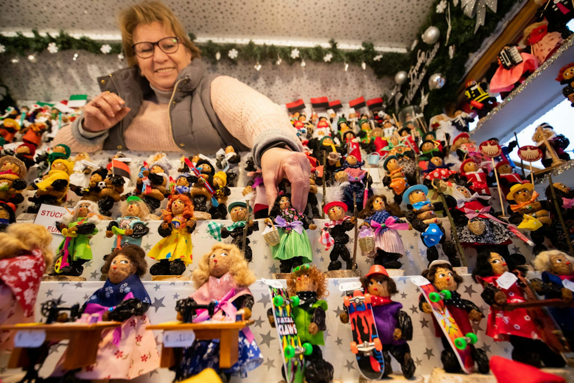 A stall holder arranging a display of prune men, figures made from dried plums, at Nuremberg Christmas Market, Germany
