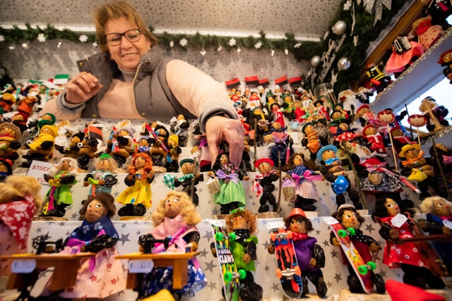 A stall holder arranging a display of prune men, figures made from dried plums, at Nuremberg Christmas Market, Germany