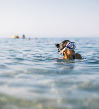 Woman wearing a snorkel scuba mask while swimming in the sea, Greece