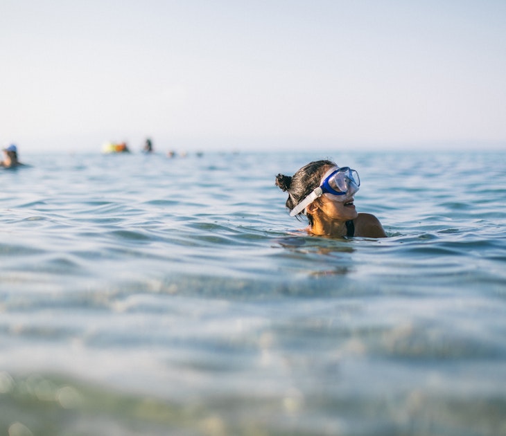 Woman wearing a snorkel scuba mask while swimming in the sea, Greece