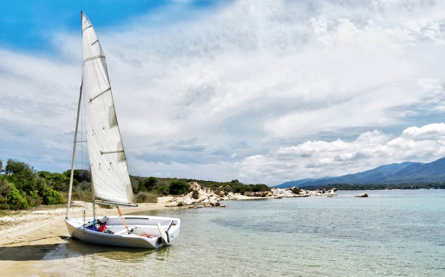 A small white sailing boat moored on a beach in Halkidiki, Greece