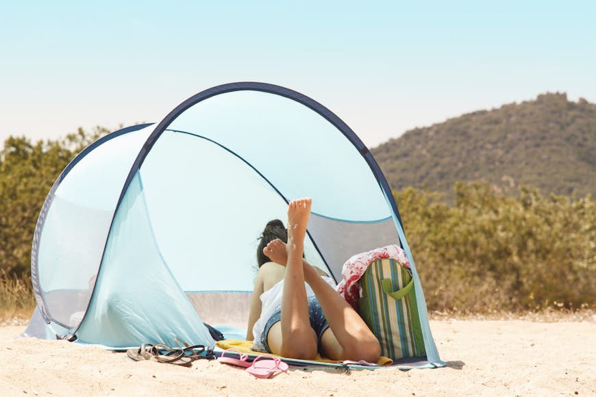 A solo figure in a tented shelter on a golden sandy beach