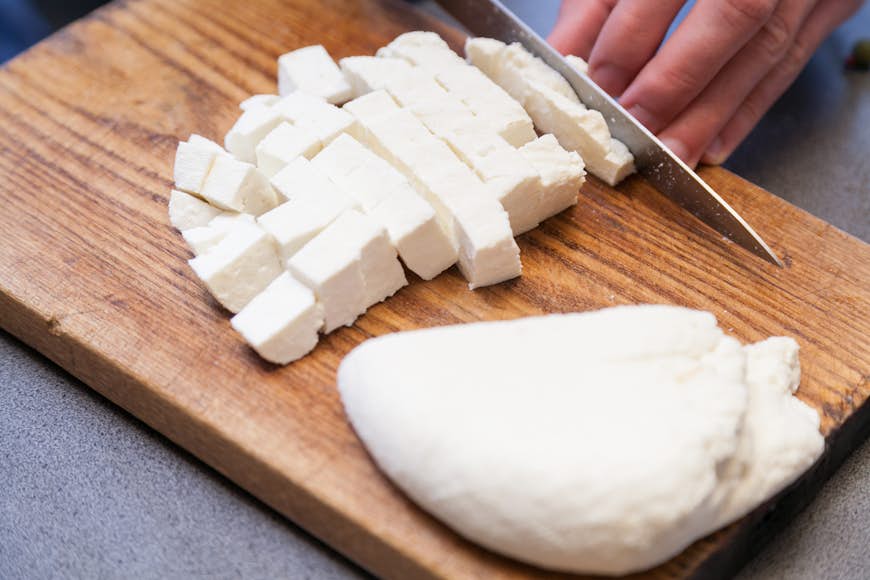 Cutting paneer into pieces on wooden board