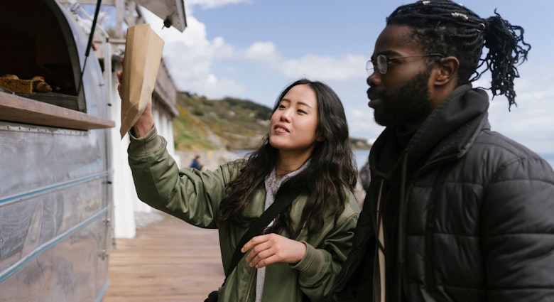 Young Black and Asian couple are Travelling in Ireland and Stopping By an Itinerant Coffee shop van to order food and Drinks

