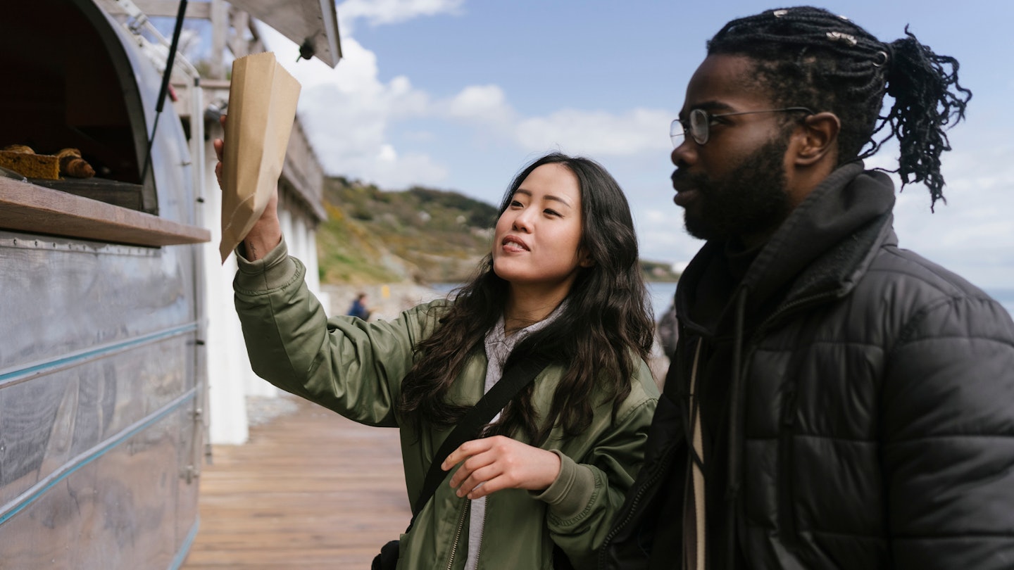 Young Black and Asian couple are Travelling in Ireland and Stopping By an Itinerant Coffee shop van to order food and Drinks