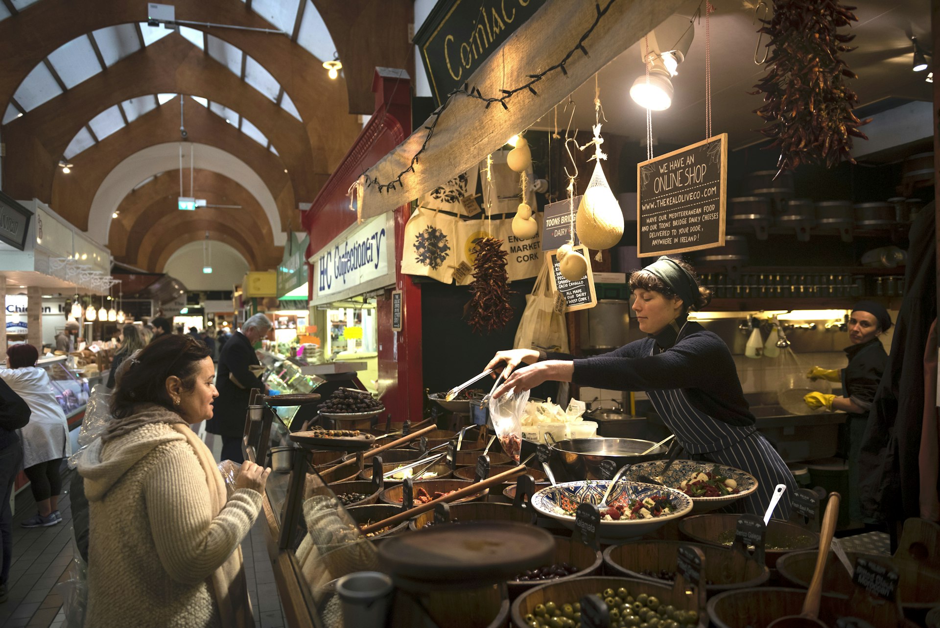 A woman serves food to a customer at the English Market, a municipal food market in the city center of Cork, Ireland. 